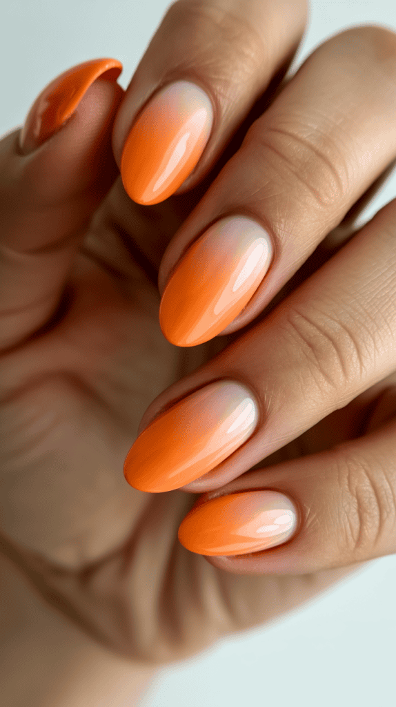 Bright orange summer nails with a glossy finish on well-manicured fingers.
