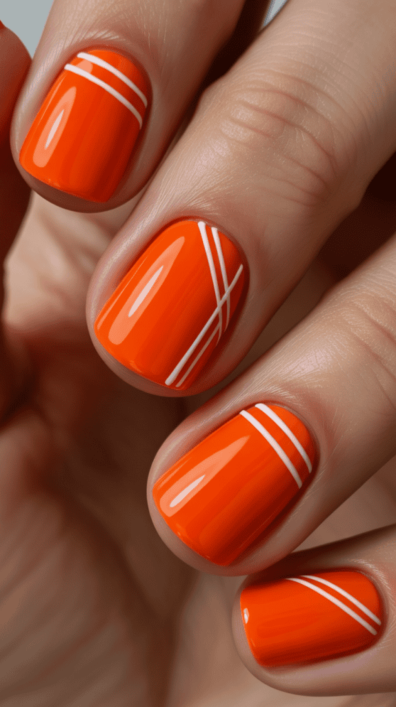 Bright orange nail polish with white stripe accents for summer style.