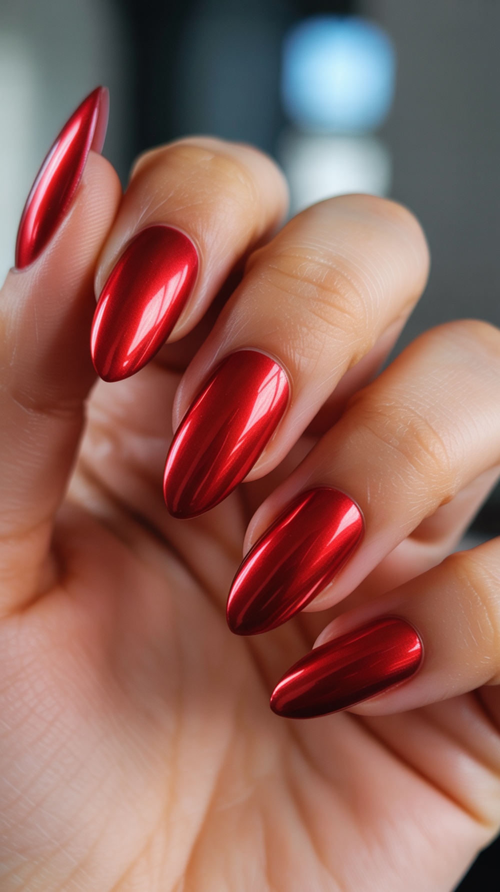 A close-up of red chrome nails with a glossy finish, showcasing their metallic shine and bold color.