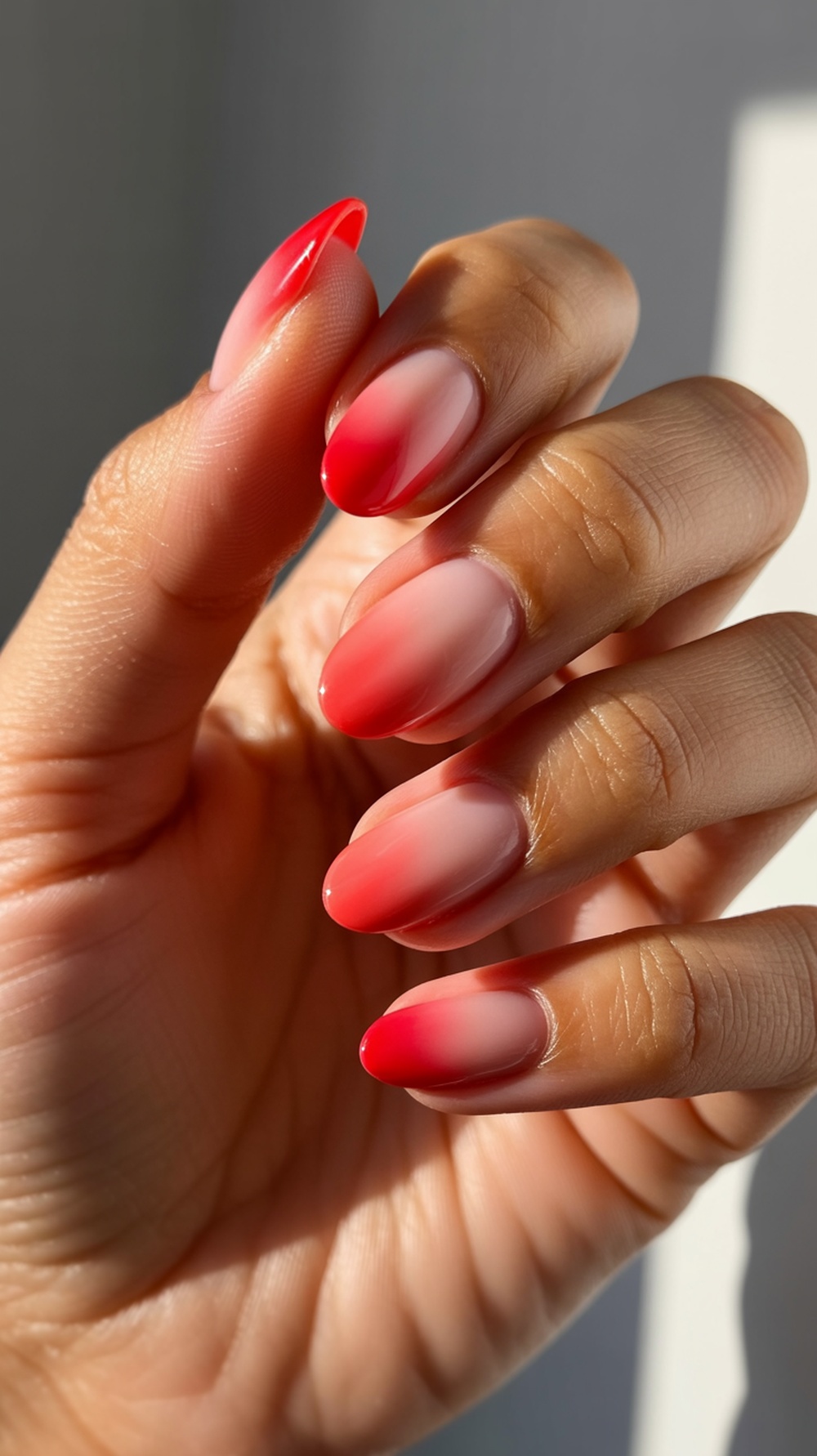 Close-up of red ombré sunset nails showcasing a gradient from pink to red.